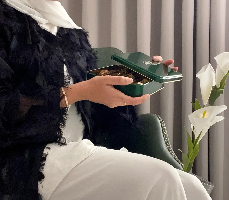A woman opening the green Al Qanz gift tin